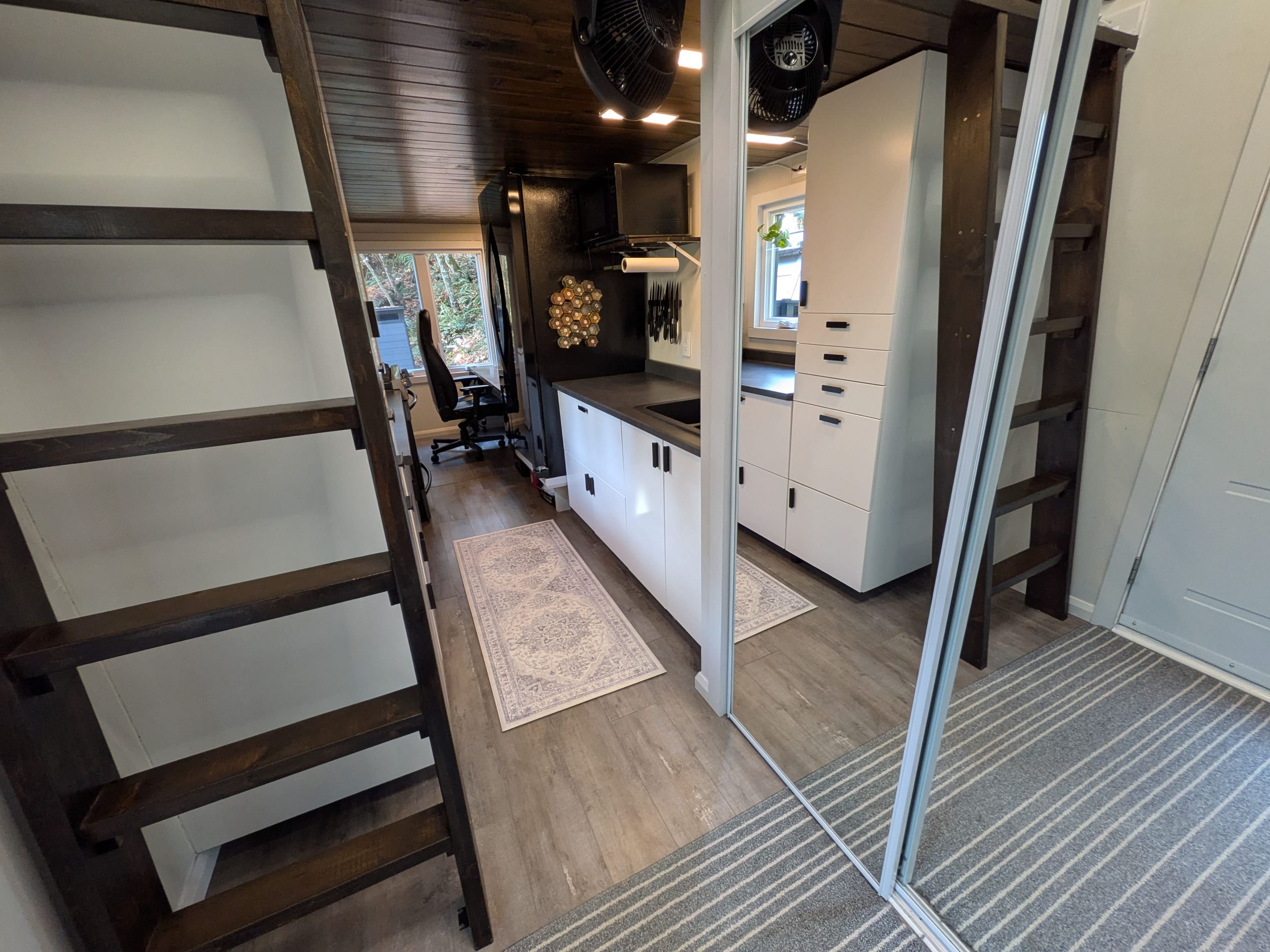 View from the stairs across the kitchen and living area toward the loft ladder