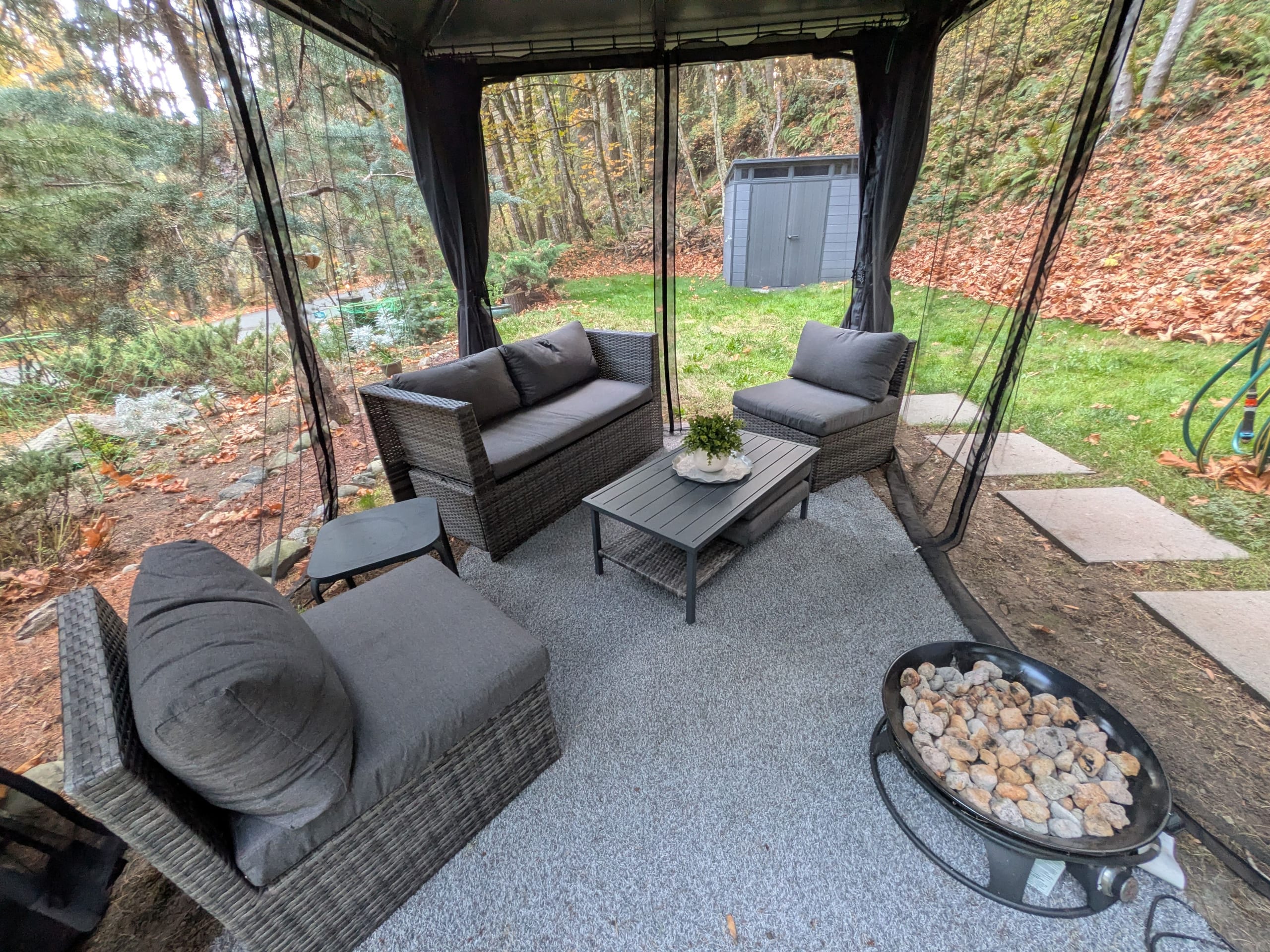 Screened gazebo with sofas, coffee table and fire bowl